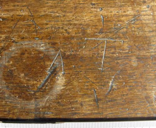 6. Letters A and T, probable initials. Middle aisle bench.