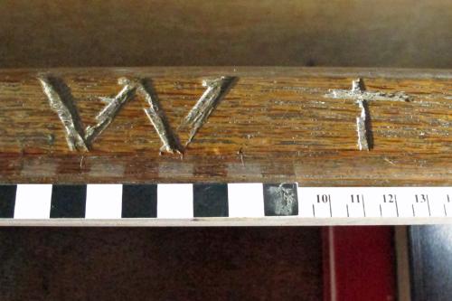 10. Deeply carved W and cross on bench at back of north aisle. Initial of the seat occupant?